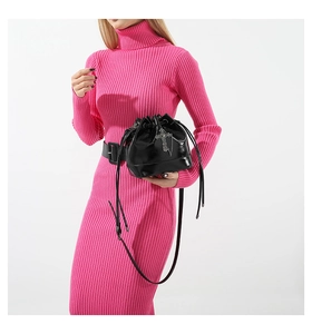 Detail of a black gothic drawstring bucket bag with silver cross and chain on a pink dress
