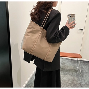 Detail view of large nylon tote bag in khaki finish being worn by model on shoulder
