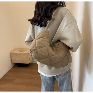 Detailed back view of a model wearing an olive green quilted puffer hobo bag