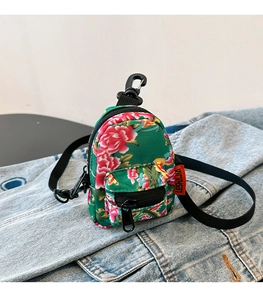 Mini floral canvas backpack pendant with zipper detail on blue denim background