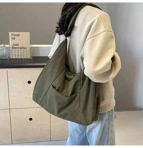Macro side view of large army green nylon tote bag on shoulder for commute usage