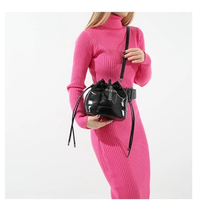 Detail view of black glossy PU leather bucket bag with silver cross on a pink dress