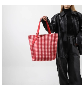 Dettaglio della borsa tote in tweed a quadri bianchi e rossi portata dalla modella