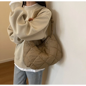 Close-up of quilted nylon shoulder bag in tan with silver zipper on female model