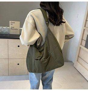 Detail of olive green nylon crossbody bag showing the large crescent shape and wide strap