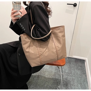 Polished khaki nylon tote bag detail featuring reinforced faux leather straps and trim