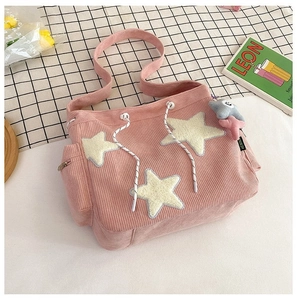 Detail van roze corduroy draagtas met gele sterpatches en pluizige sterren sleutelhanger