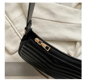 Detail of smooth golden zipper and horizontal quilted leather on black shoulder bag