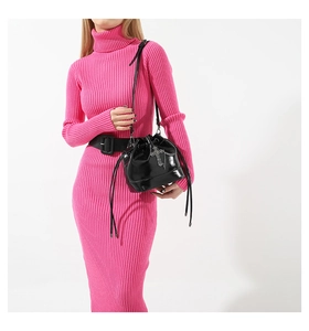 Detail of black drawstring bucket bag with glossy patent leather and silver cross charm