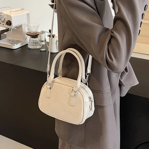 Detail of a creamy white glossy PU leather Boston bag with silver zipper and slim strap