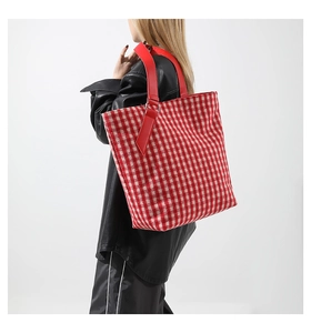 Dettaglio borsa tote in lana a quadri rossi e bianchi con tracolla larga in pelle rossa