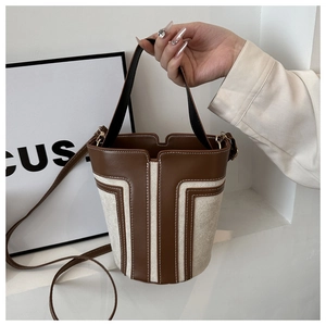 Dettaglio della borsa a secchiello in pelle marrone e tela beige con cucitura a T