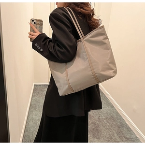 Detail view of large nylon tote bag with reinforced trim shown on female model shoulder