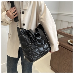 Detail of black quilted puffer tote bag showing large square texture and nylon straps