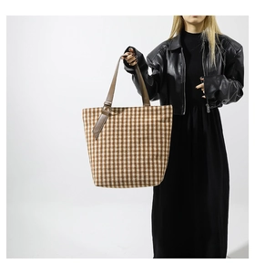 Dettaglio della borsa tote in tweed pied-de-poule con manici in pelle marrone su modella