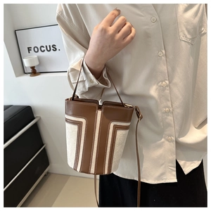 Dettaglio della borsa a secchiello minimalista in tweed con cuciture in pelle marrone scuro