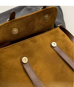 Detail view of brown velvet bag showing golden magnetic buckle and leather trim