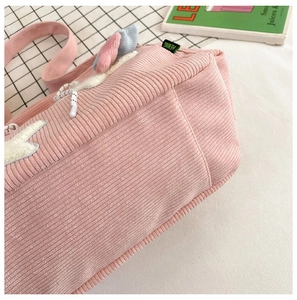 Gedetailleerde close-up van de roze corduroy tote tas met groen geweven label en textuur