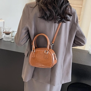 Elegant woman wearing a brown glossy PU leather tote bag with silver hardware in a cafe