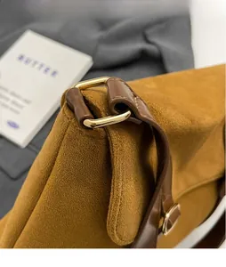 Close-up of polished gold metal ring hardware on a brown suede texture handbag strap