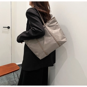 Silver-grey nylon tote bag with long shoulder straps shown on a model for daily commute