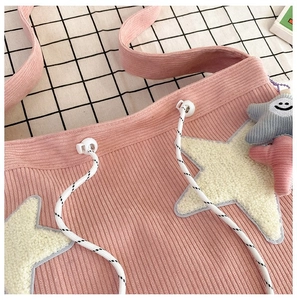 Detail van roze corduroy draagtas met geborduurde ster en vrolijke smiley-hanger