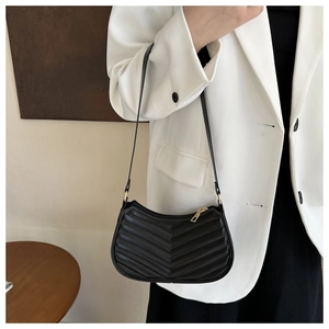 Detail of black V-quilted faux leather shoulder bag with elegant gold zipper and strap