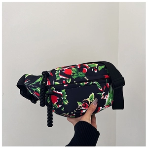 Close-up of black nylon crossbody bag featuring a vibrant red rose and green leaf print