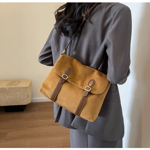 Close-up of retro brown suede crossbody bag with leather straps and metal buckles