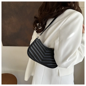 Detail of black V-quilted faux leather underarm bag with elegant gold metal hardware