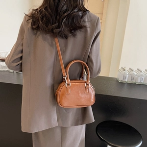 Detailed shot of a vintage brown PU leather mini bowling bag worn as a crossbody purse