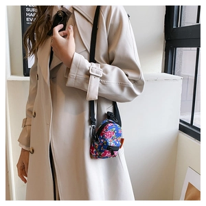 Blue floral mini backpack pendant with rose pattern and crossbody strap on a model