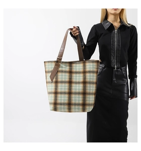 Dettaglio della borsa tote in lana a quadri con manici in pelle su modella moda