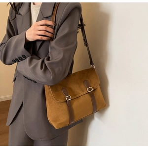 Macro view of vintage brown suede shoulder bag with premium leather straps and gold buckles