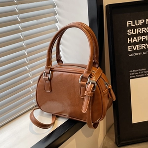 Detail of a brown PU leather Boston bag with silver hardware on a white window sill