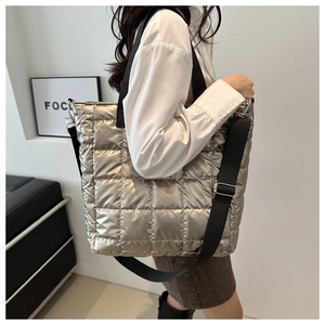 Detail of silver quilted tote bag with metallic finish and adjustable black shoulder strap