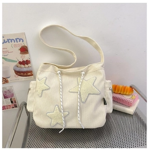 Detail van de gebroken witte corduroy draagtas met gele sterborduurders en trekkoordsluiting