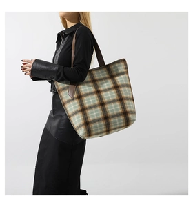 Dettaglio della borsa tote in lana scozzese verde e marrone con manici in pelle