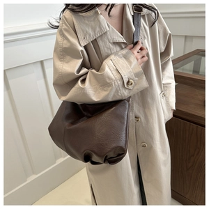 Detail einer weichen Vintage-Ölwachs-Ledertasche getragen zu einem beigen Trenchcoat