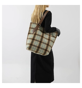 Vista dettagliata della trama in tweed classico e della tracolla in pelle marrone della borsa
