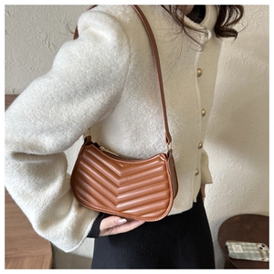 Detail of brown quilted faux leather hobo bag showing V-shape stitching and gold zipper