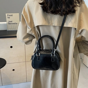 Close-up of black glossy faux leather Boston bag with silver hardware and shoulder strap
