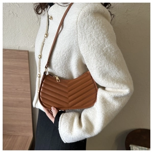 Detail of caramel brown quilted PU leather hobo bag on a white tweed jacket outfit
