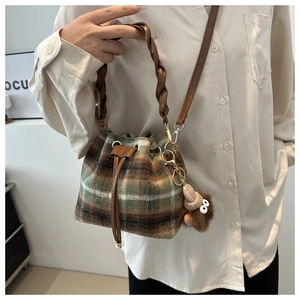 Detail of checkered bucket bag featuring drawstring closure and plush doll pendant