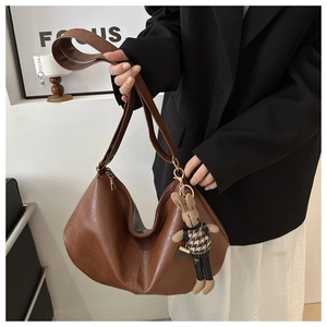 Nahaufnahme der braunen Vintage-Ledertasche mit niedlichem Strickhasen-Anhänger