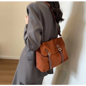 Detail view of a vintage brown faux suede crossbody bag with decorative leather straps