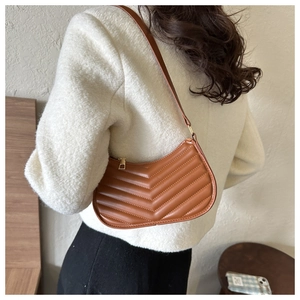 Detail of caramel PU leather underarm bag with V-quilted texture on model shoulder