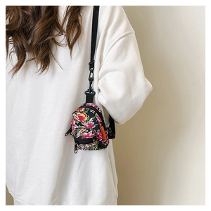 Detail of floral mini backpack charm with vintage pattern on a white sweater background