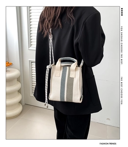 Detail view of canvas striped tote bag with cotton rope handles on model in casual suit