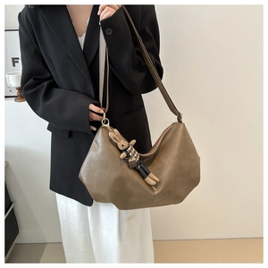 Detail einer dunkelkhakifarbenen Hobo-Bag aus Leder mit einem niedlichen Hasenanhänger
